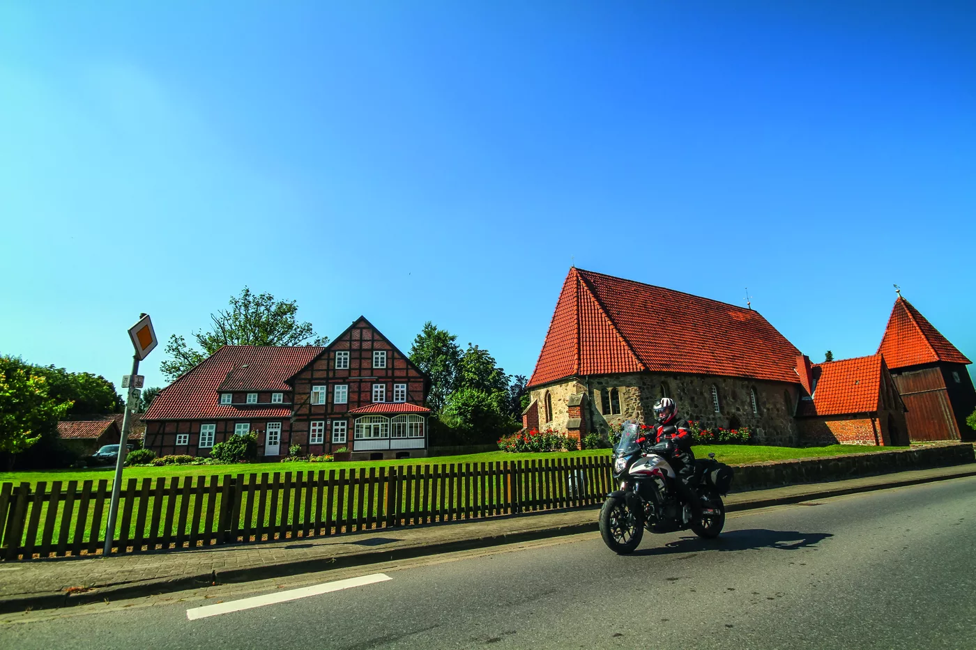 Motorrad auf der Dorfstraße vor Backsteinhäusern und Kirche